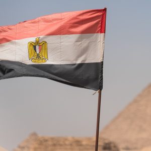 National flag of egypt waving in the wind with the pyramid of giza in the background, representing egyptian tourism and history