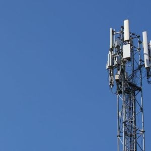 Cell phone tower antennas against a clear blue sky background.